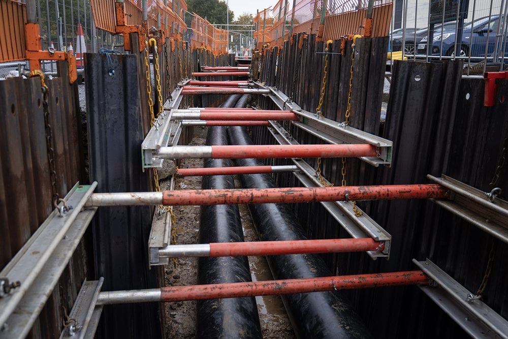 Twin district heating pipes laid in a long trench beside a city street.